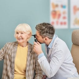 Older woman getting her ears checked by a doctor.