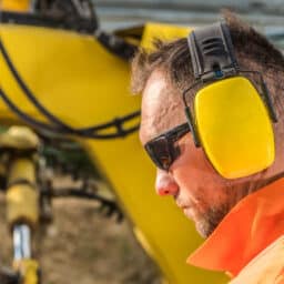 Man wearing earmuffs as hearing protection at a construction site.