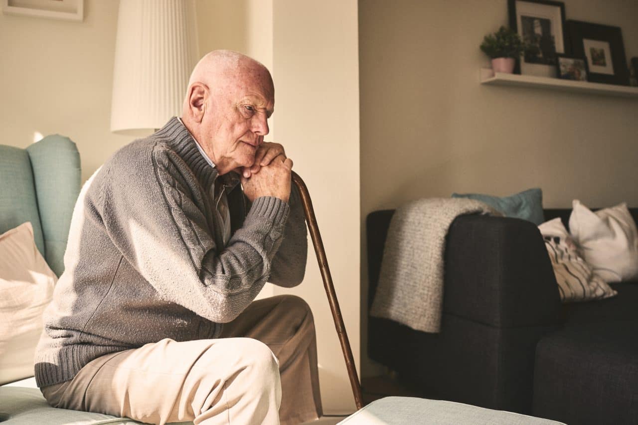 Thoughtful-looking senior man sitting alone at home.