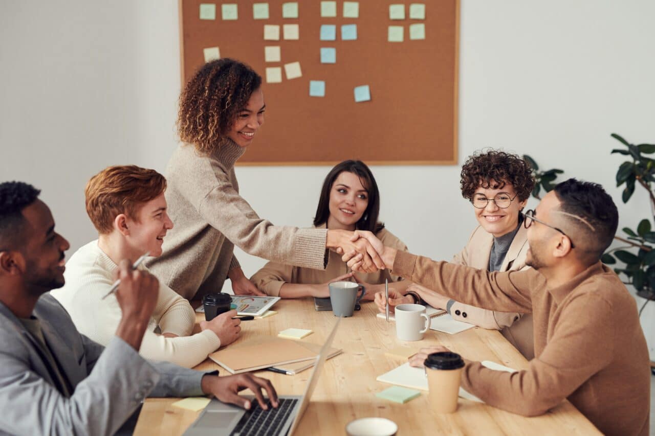 Woman shaking hands with coworker at a meeting.
