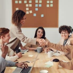 Woman shaking hands with coworker at a meeting.