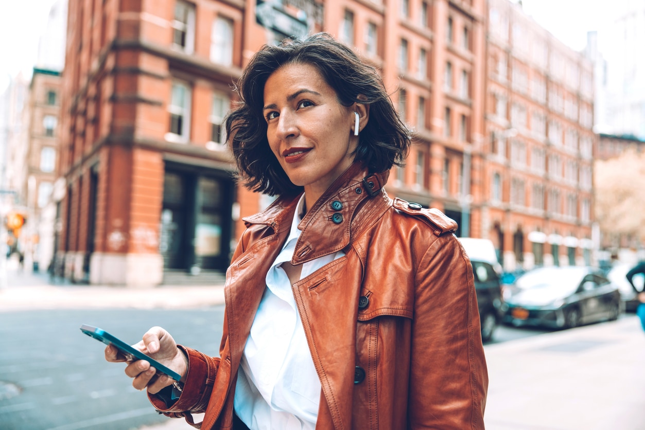 Woman wears airpods while walking through city