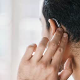 Man showing off new hearing aid, view from the back of the head.