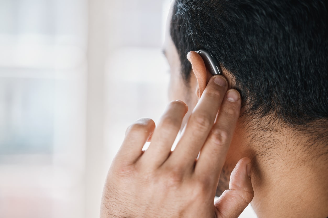 Man showing off new hearing aid, view from the back of the head.